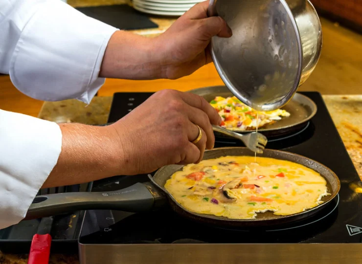 Kucharz na bieżąco przygotuje omlet z ulubionymi składnikami