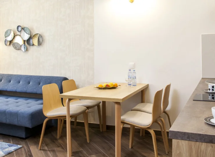 Apartament junior posiada salon z rozkładaną sofą, kącikiem jadalnym i TV