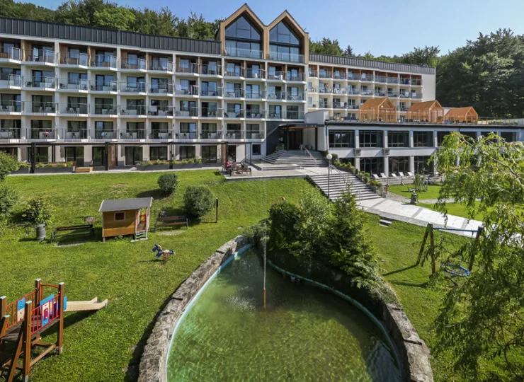 Hotel otacza zielony teren z placem zabaw i oczkiem wodnym