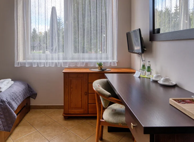 Za oknami widać ogród, łąki lub las