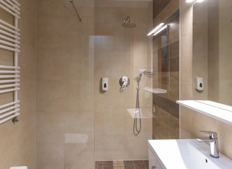 W łazience jest kabina prysznicowa i suszarka do włosów