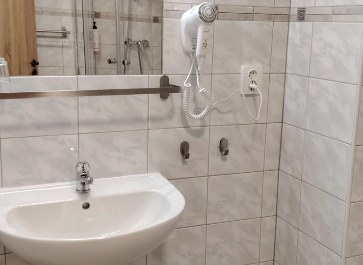 W łazience jest kabina prysznicowa i suszarka do włosów