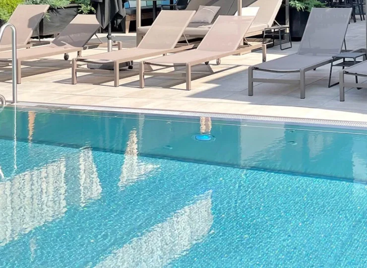 Zewnętrzny basen z podgrzewaną wodą jest otoczony leżakami