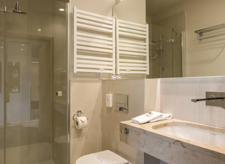 W łazience jest kabina prysznicowa, suszarka do włosów i kosmetyki