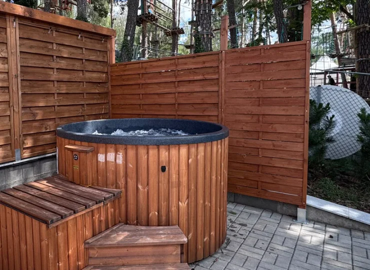 Obok sauny jest jacuzzi, a za płotem park linowy