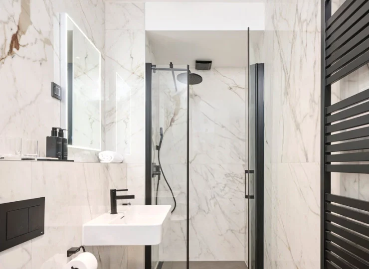 W nowoczesnych łazienkach jest kabina prysznicowa, suszarka i kosmetyki