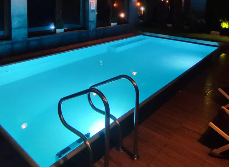 Obok basenu stoi kilka leżaków