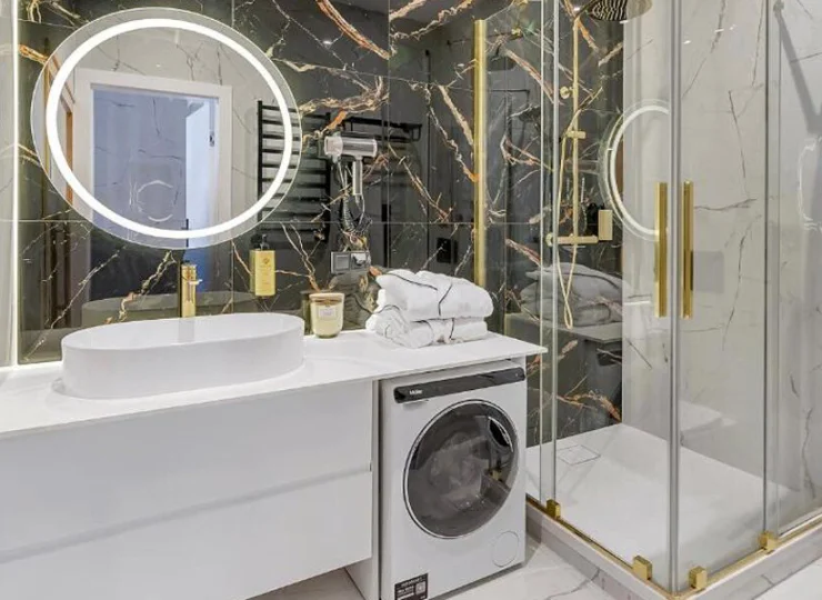Łazienka z prysznicem i pralką w apartamencie 2+2 z sauną