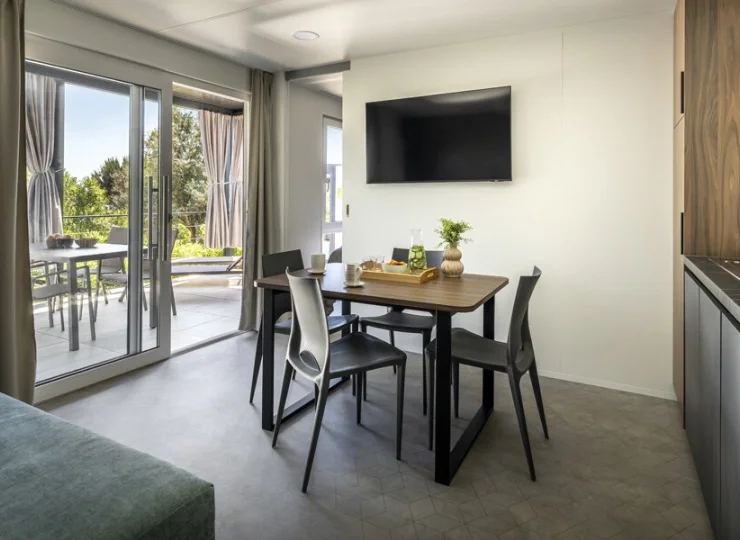 Domek ma pokój dzienny z kuchnią i wyjściem na taras