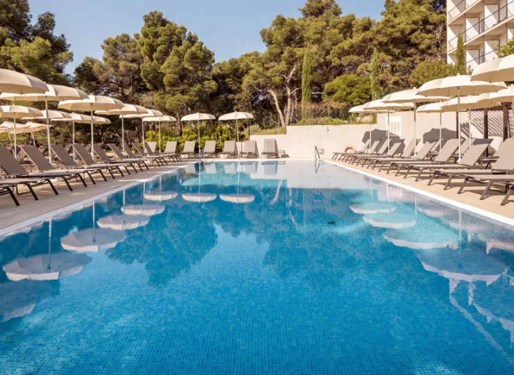Hotel posiada zewnętrzny basen otoczony parasolami i leżakami