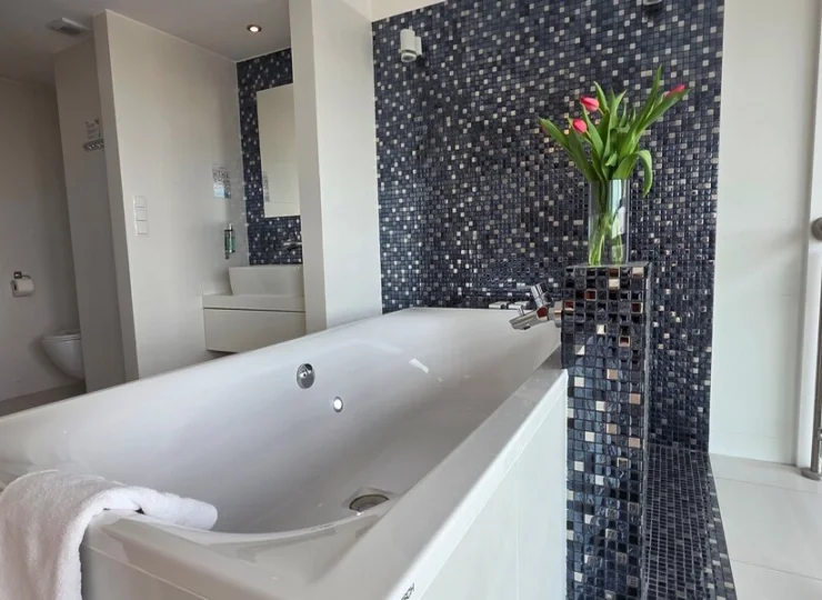 Apartament posiada otwartą łazienkę z wanną z hydromasażem tuż przy łóżku