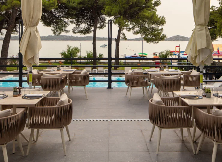 Obok basenu jest restauracyjny taras ze stolikami