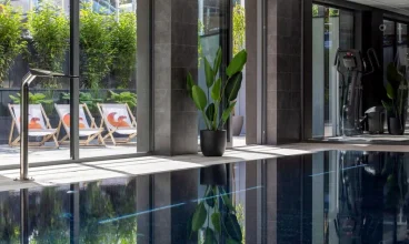 Przeszklona ściana basenu wychodzi na zielony ogród