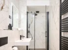 W nowoczesnych łazienkach jest kabina prysznicowa, suszarka i kosmetyki