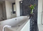 Apartament posiada otwartą łazienkę z wanną z hydromasażem tuż przy łóżku